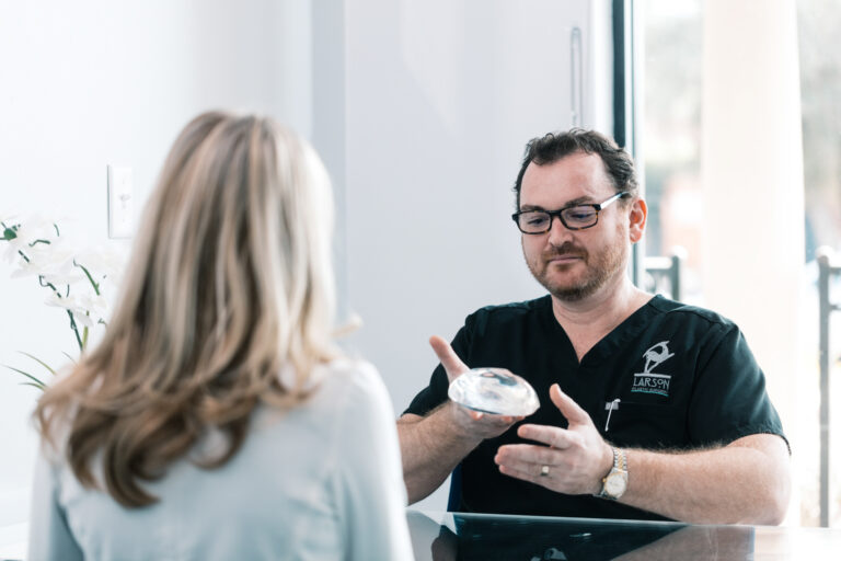Plastic surgeon holds up implant and discusses his extensive training and expertise, making him the best choice of plastic surgeon for your breast augmentation near Catalina Foothills