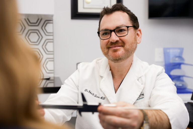 Plastic Surgeon holding up ruler to display measurements for gender affirming mastectomy in Tucson