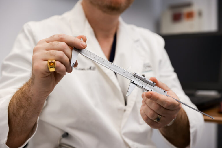 up close photo of plastic surgeon holding a ruler to help patient visualize results from their lipedema treatment in Tucson